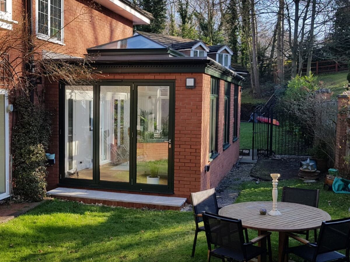 An orangery with brick pillars, French doors and a glazed roof lantern, fitted by Heritage
